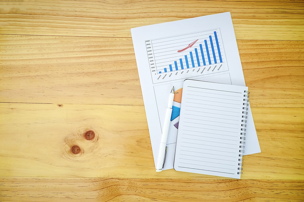 Notebook and Pen on Business Report on Wooden Table Flatlay